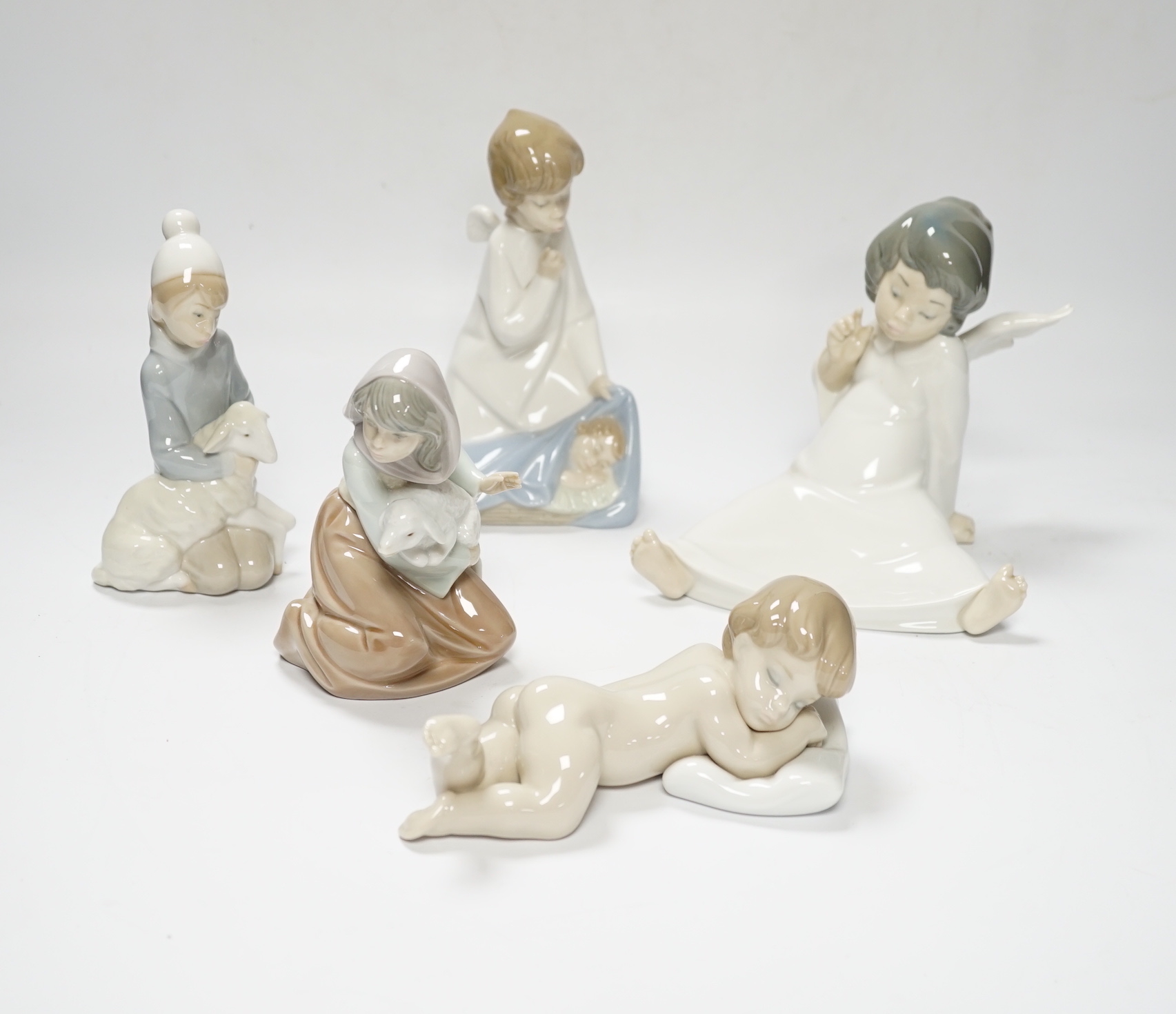 Five Lladro figures; two angelic, two nativity, one of a sleeping child and another of a girl with a lamb, all in boxed, largest 17cm high